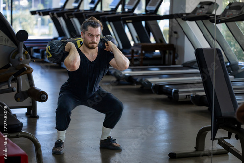 Caucasian muscular body builder sport man is practice weight training on sandbag lunges for core muscle inside gym for exercising and hyrox workout concept