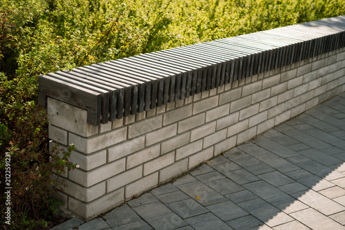 Bild auf Leinwand Wooden bench with slat seat on concrete block retaining wall in garden