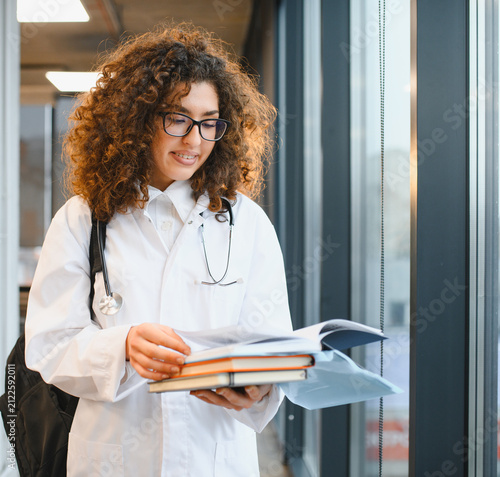 Fotografie Young medical student walking, carrying books and notes