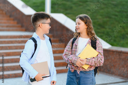 Fotografie Schoolchildren friends talking at campus while leaving class