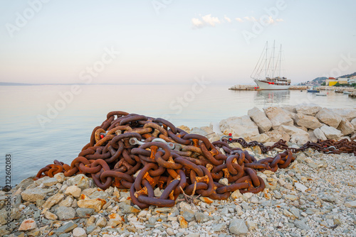 Quadro su tela Large pile of rusty metal anchor chains on a rocky shore