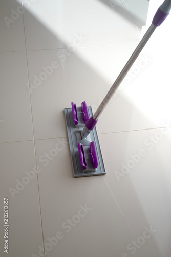 Flat wet-mop made of microfiber wipes the tiled terracotta floor, daily cleaning routine for a hygienic and healthy home
