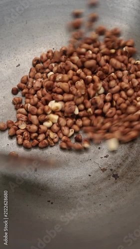Satisfying dry cooking process of brown peanut roast snack using metal spatula for active stir motion inside wok