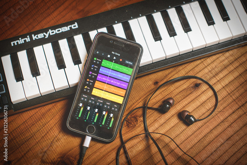 Smartphone Music Production App with Mini Keyboard and Earphones on Table