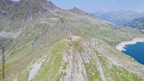Hikers on top of mountain peak with Twin lakes on background, Orobie mountains, Lombardy landscape