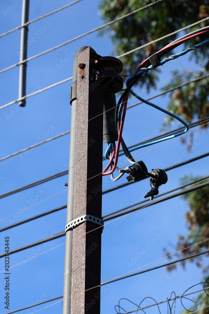 Obraz premium Close up of a weathered utility pole with electrical wires and insulators against a clear blue sky