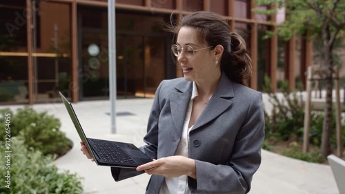 Businesswoman presenting and talking while holding a laptop outdoors