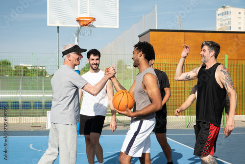 Canvas Print Group of men showing sportsmanship and teamwork on an outdoor basketball court