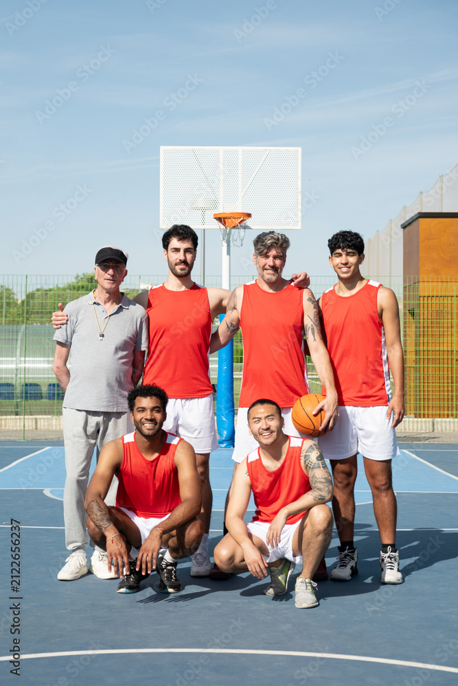 Fototapeta premium Diverse basketball team and coach smiling together on an outdoor sports court