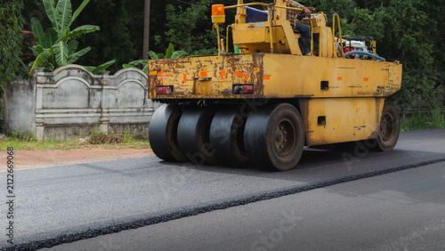 Asphalt road roller with heavy vibration roller compactor press new hot asphalt on the roadway on a road construction site. Heavy Vibration roller at asphalt pavement working. Repairing.