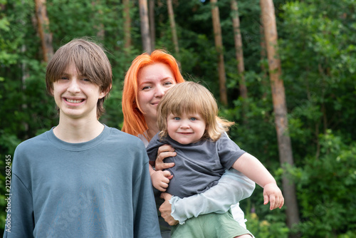 mother with teenage son and little toddler in summer forest
