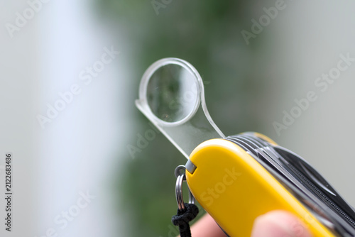 Fotografie Close up of magnifying glass tool on pocket knife with yellow handle with copysp