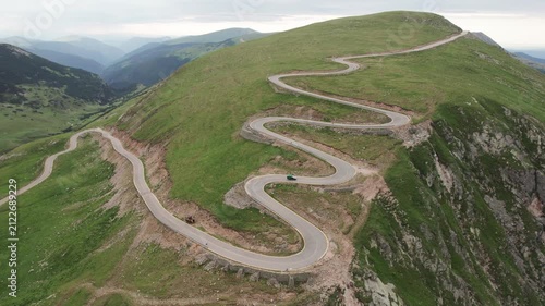 Aerial tracking shot of a car driving on the winding Transalpina mountain road in Romania