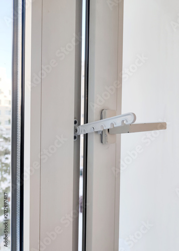 White plastic window with handle in ventilation position. Close-up of window frame and hardware. restrictor for plastic windows