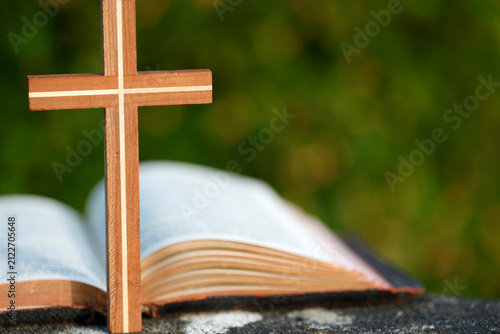 Photography Faith and devotion symbolized by a hand-carved wooden cross placed in front of an open Bible