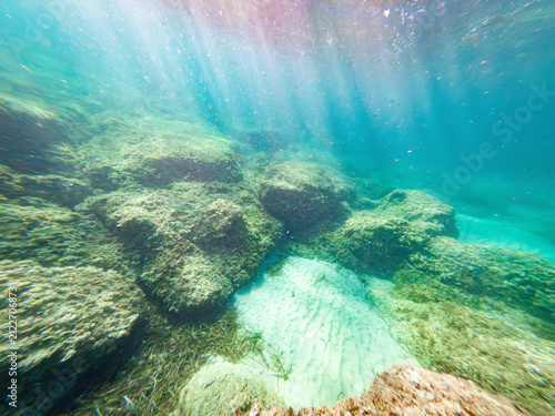 Underwater view of Sardinia seabed with rocks sand and sunlight rays