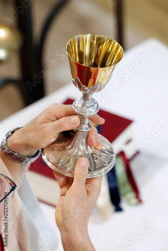 Bild auf Leinwand A priest celebrates the Eucharist, holding a golden chalice during a Mass at the Sanctuary of the Blessed Fountain