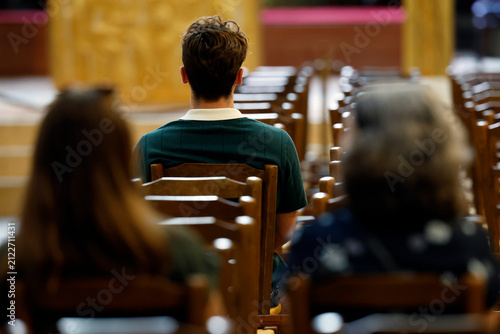 Notre-Dame Church. People sitting on wooden chairs are praying in silence.