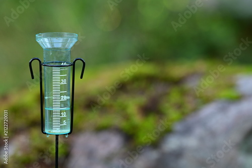 Rain Gauge Measuring Rainfall in Garden with Green Bokeh Background