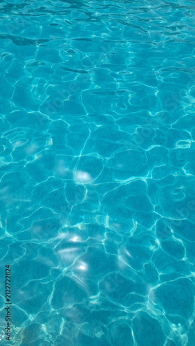 Crystal clear swimming pool water with turquoise ripples and sunlight reflections