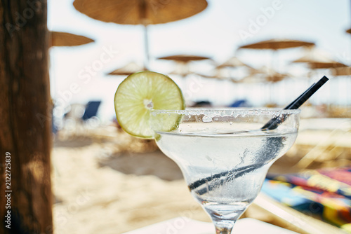 Close-up of a refreshing margarita cocktail with lime slice and salt rim at beach