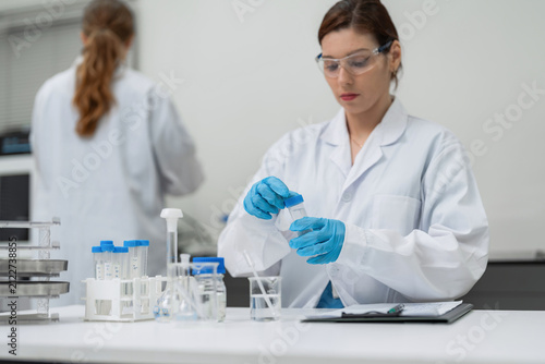 Cuadro en lienzo Female scientist in protective gear examining liquid sample in vial at modern laboratory for pharmaceutical research, medical healthcare testing, and commercial biotechnology development