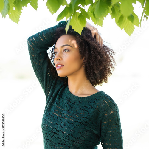 Portrait of beautiful young woman with curly hair posing in sunny park