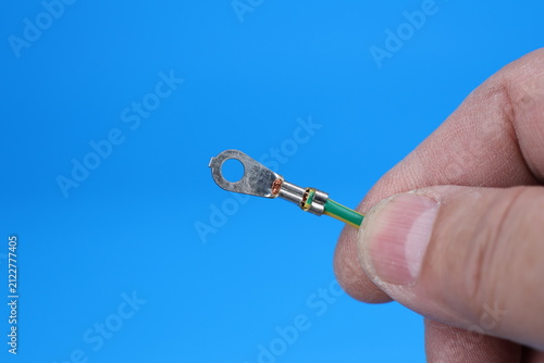 The hand holds an electric copper wire with a metal tip of a round shape. 