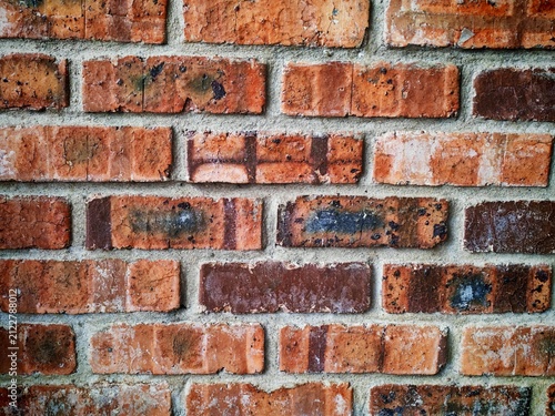 Bild auf Leinwand Front view of an aged red brick wall featuring natural wear, mortar lines, and rough texture suitable for construction and architectural backgrounds