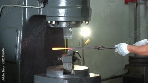 Crafting Metal: The High-Speed Action of a Hydraulic Press Forging a Hot Iron Bar into Shape at a Workshop, Showcasing Metalworking Techniques and Precision