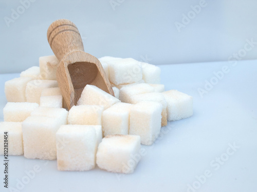 Canvas Print White sugar cubes in a small wooden scoop for sweetening