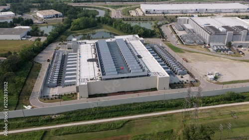 Aerial view of large data center facility with rooftop cooling units and surrounding industrial infrastructure