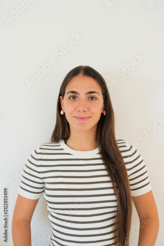 Fotografie Young brunette woman with long hair smiling at the camera, wearing a casual stri