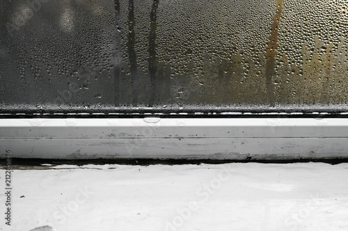 Water drops cover window glass inside home. High humidity causes moisture damage on windowsill. Damaged window pane shows condensation problems in cold. drops of moisture run down wet glass. concept
