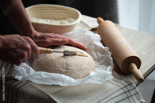 Fotografie Scoring Sourdough Bread Dough with Bread Lame Before Baking