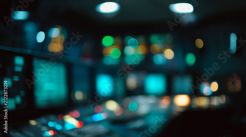 Defocused dark control room at night with glowing cyan and green console bokeh
