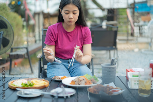 Young woman eating a meal outdoors at a casual restaurant with various dishes