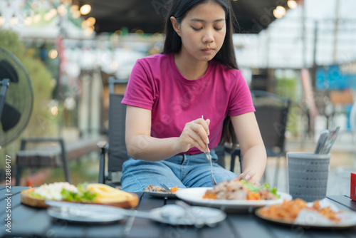 Young woman enjoying a meal at an outdoor restaurant during the day