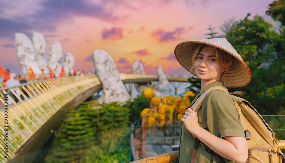 Fototapeta premium Young caucasian female tourist at golden bridge in ba na hills, Da nang, Vietnam during sunset