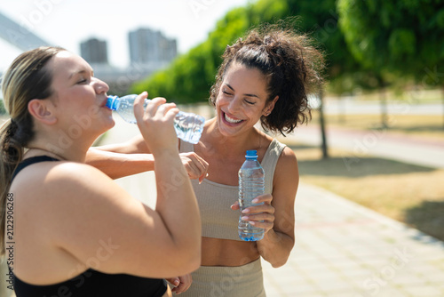 фотографія Women hydrating after outdoor workout sharing a laugh