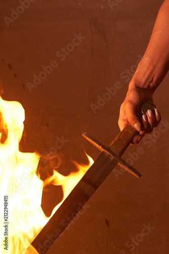 Close-up of a female warrior's hand holding a flaming sword