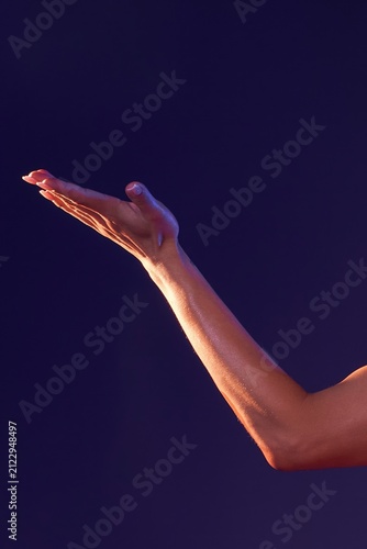Elegant female hand and arm with dramatic lighting on a dark purple background