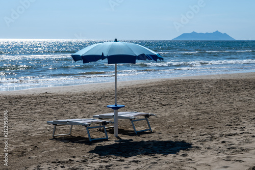 Obraz na płótnie Blue beach umbrellas and empty sunbeds line on sandy shore near Sperlonga, Italy