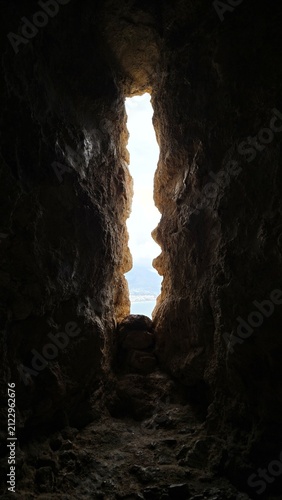 Bild auf Leinwand Vertical shot of a rugged stone loophole window inside a dark medieval cavern fo