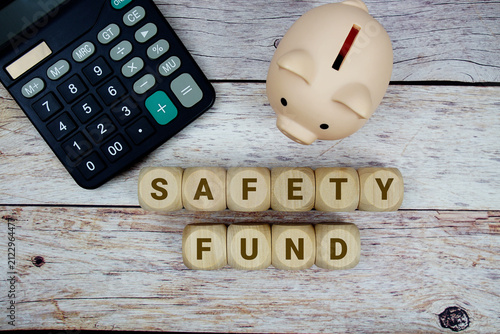 Фотография Safety Fund alphabet letters with calculator and piggy bank on wooden background