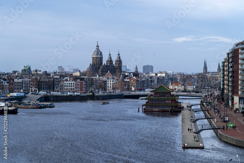 Moored passenger boats, houseboats, and historic drawbridge on Amstel river in Amsterdam