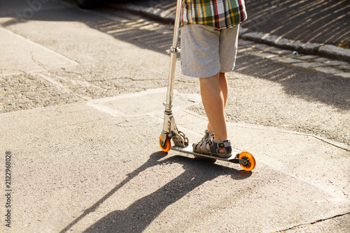 Canvastavla Child riding kick scooter on sunny street