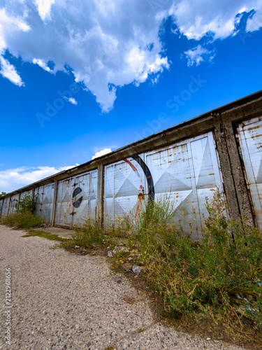 Quadro su tela Row of old metal garages along concrete path