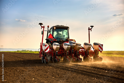 Farmer driving tractor seeding fields, cultivating land during agricultural season
