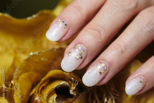 Shimmering gold manicure. A hand displays beautifully manicured gold particles nails adorned with glittering polish. 